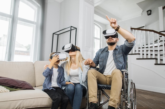 Father in wheelchair teaching wife and son using VR goggles