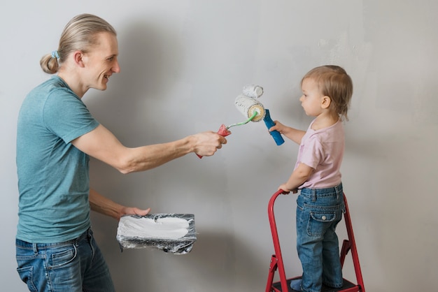 部屋で装飾と再設計をしている子供を持つ父親