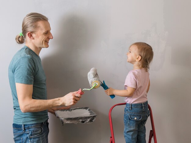 Father with child paint wall in new house