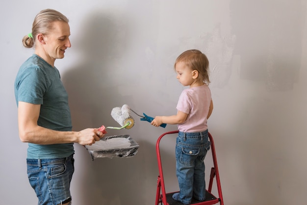 新しい家の子供ペイントの壁を持つ父