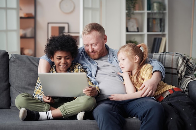 Photo father with children using laptop at home