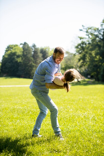 Father with cute little daughter having fun on the grass at the park