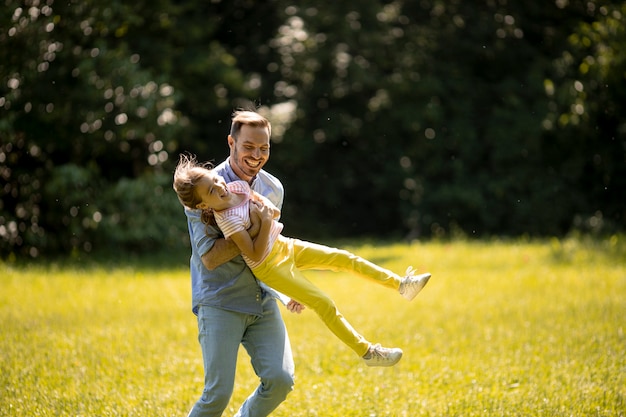 Padre con la piccola figlia carina che si diverte sull'erba al parco