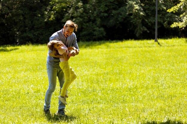 Father with daughter having fun on the grass at the park