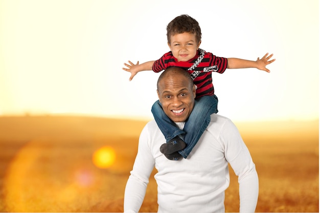 Father with daughter on piggyback on field background