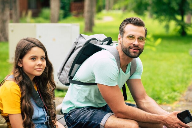 father with gray backpack and little daughter