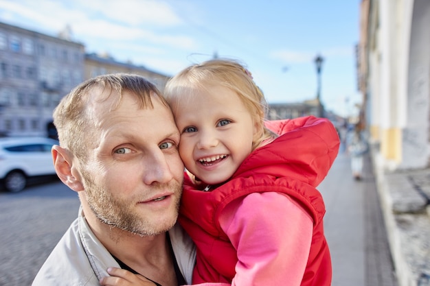 Father with happy child walks in city center