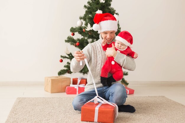 Father with his baby boy wearing Santa hats celebrating Christmas.