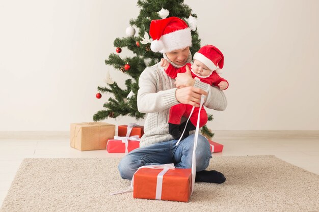 Father with his baby boy wearing Santa hats celebrating Christmas