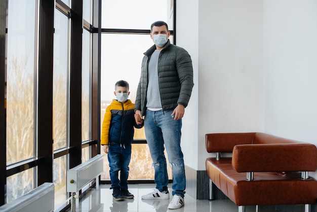 Отец с ребенком стоит в маске во время карантина. Пандемия, коронавирус.