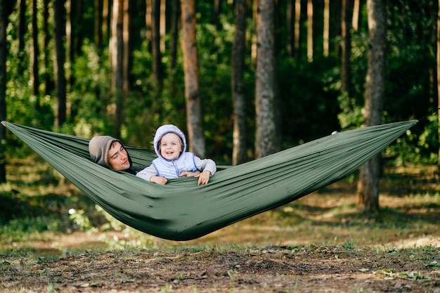 Father with his little daughter lying in hammock at nature,