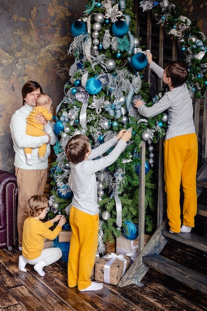 Father with his sons decorate the Christmas tree at home