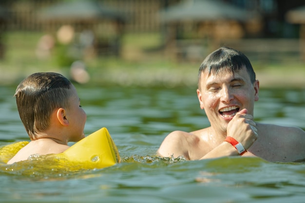 Father with kid having fun in water swimming together