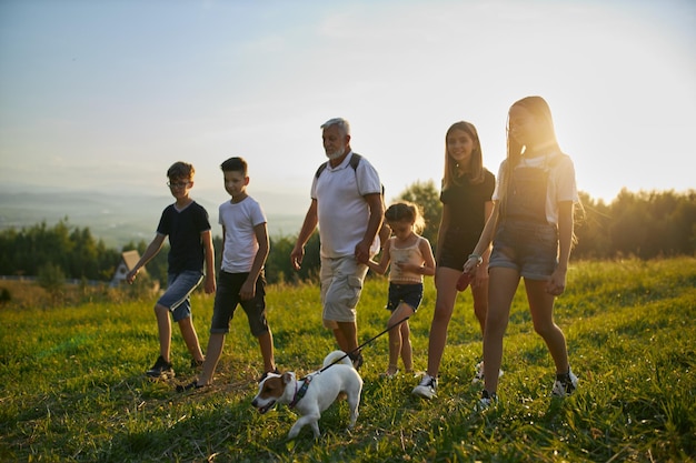 Father with kids and dog walking along field in countryside