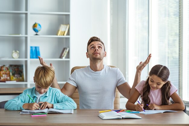 The father with kids doing homework at the desk