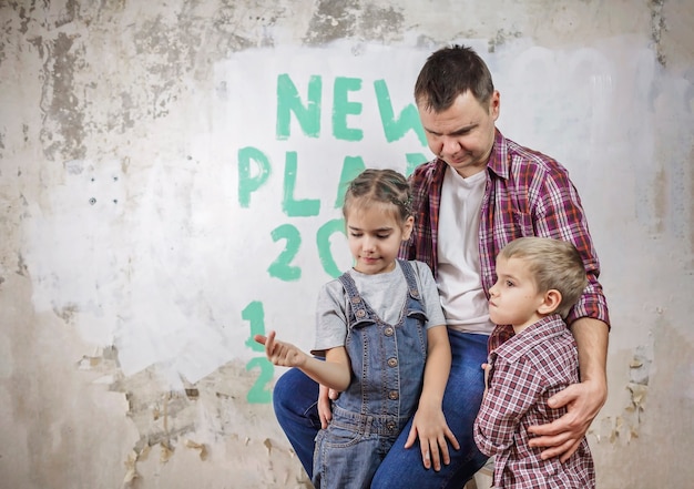 Father with kids repairing room together, unhanging wallpaper and planning new year on wall