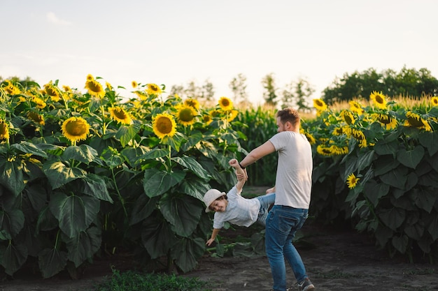 Father with little baby son in sunflowers field during golden hour dad and son are active in nature