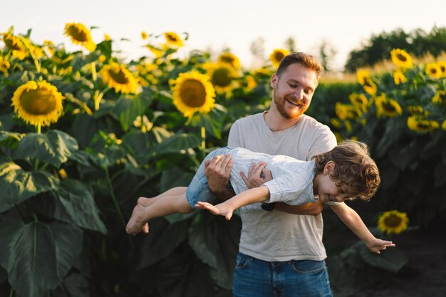 Father with little baby son in sunflowers field during golden hour Dad and son are active in nature