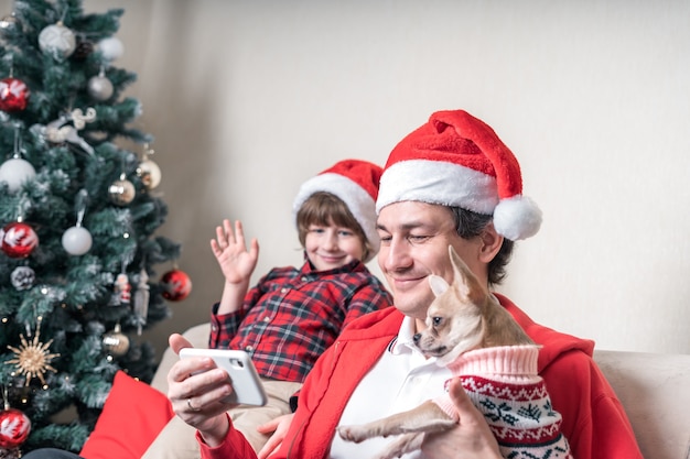 Father with son and dog having a video call on Christmas day at smartphone