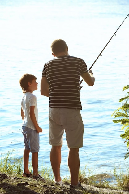 Father with son fishing from riverside