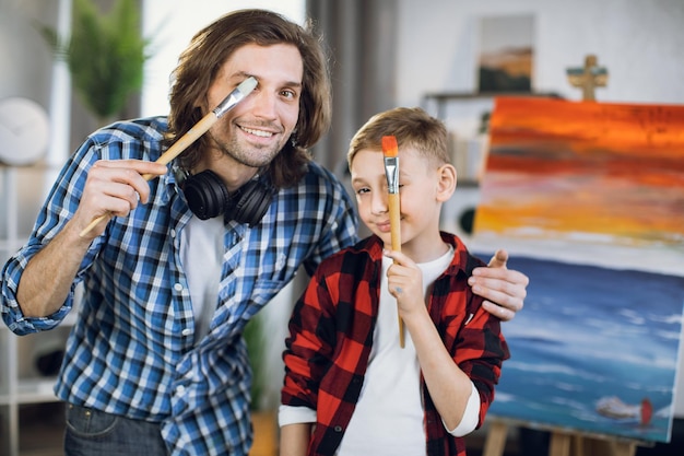 Photo father with son having fun while drawing on easel