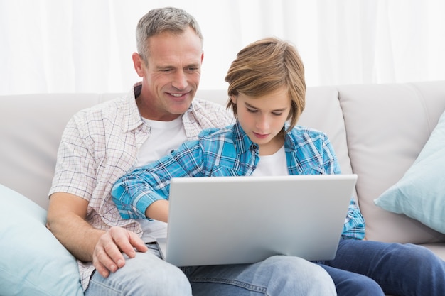 Father with son sitting on the couch using laptop