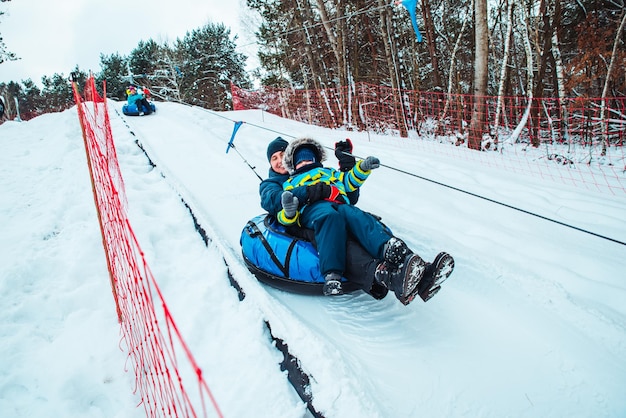 Father with son on snow tube pull up to hill