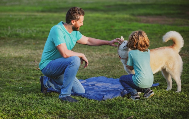 Father with son walk with pet dog and enjoy warm summer day child with her pet friend