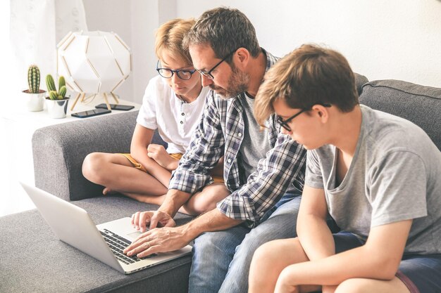 Photo father with sons sitting on sofa while using laptop