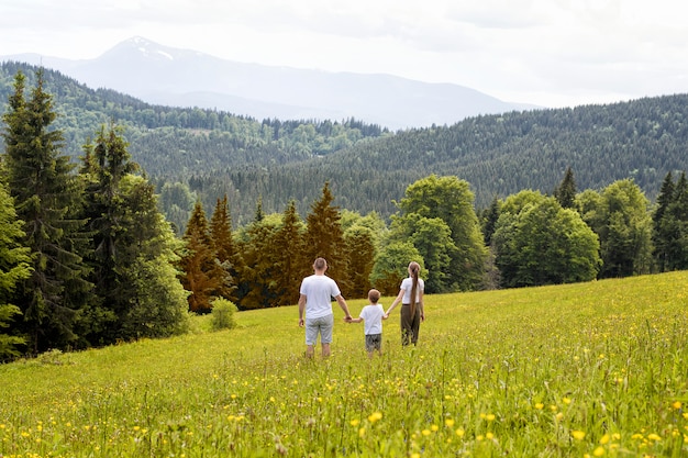 Father with young son and mother stand hand in hand on a green field