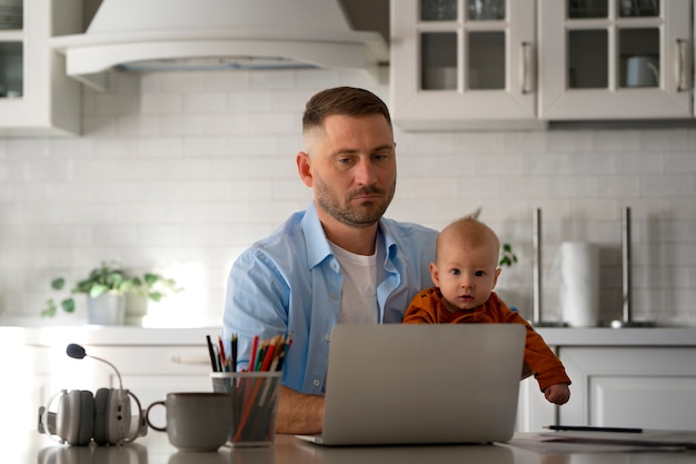 Foto padre che lavora da casa cercando di bilanciare la vita familiare con il figlio e il lavoro