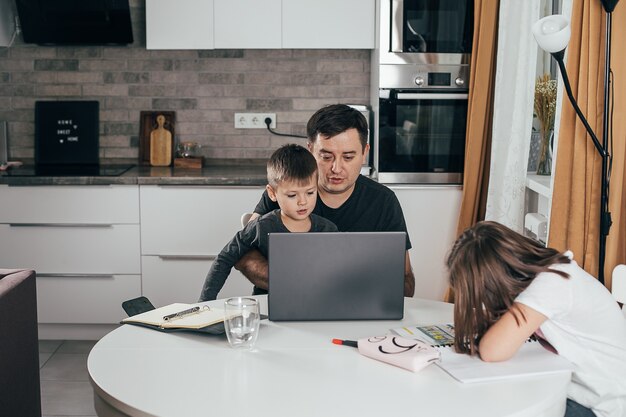 Father working from home with children at kitchen table