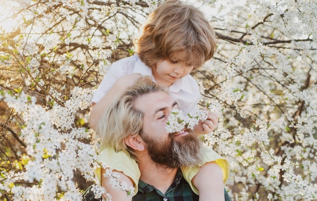 Fathers day child with dad in spring park happy father and son shoulder ride summer on the nature