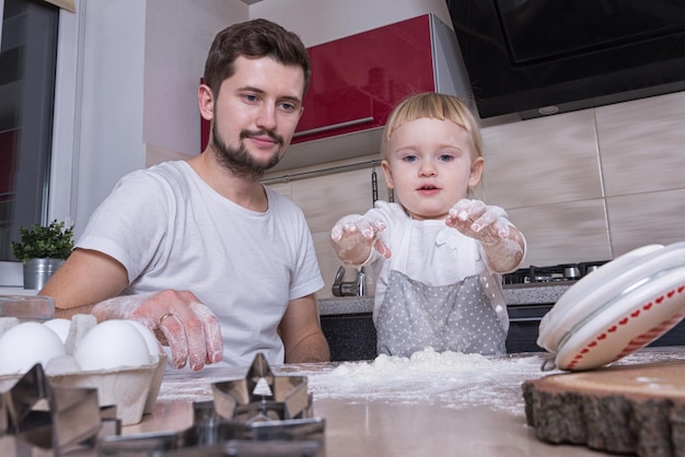 Fathers day A tiny sweet girl with blond hair spends time with her dad cooking in the kitchen