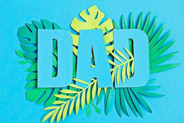 Fathers Day. Word Dad over paper cut tropical leaves and blue wall. Greeting card, invitation.