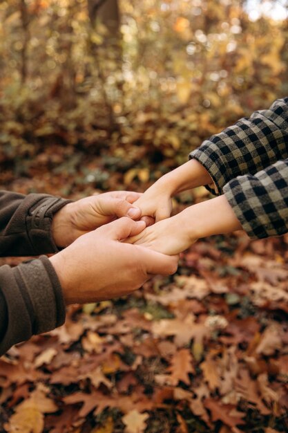 Foto padri e figli mani vicino sullo sfondo dell'autunno giallo nel parco supporto dei genitori per il bambino genitorialità e una famiglia felice