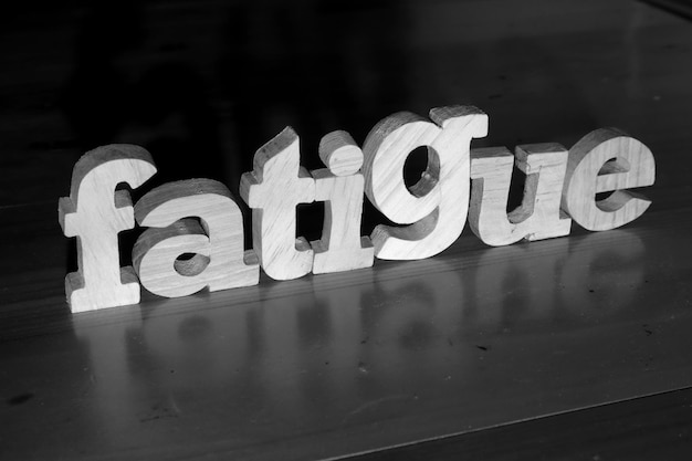 Photo fatigue text words typography written with wooden letter on black background