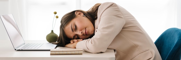 노트북 위에서 낮잠을 자는 피곤한 여성
