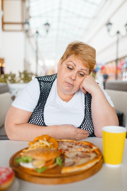 Foto donna grassa che mangia pizza nel ristorante fastfood