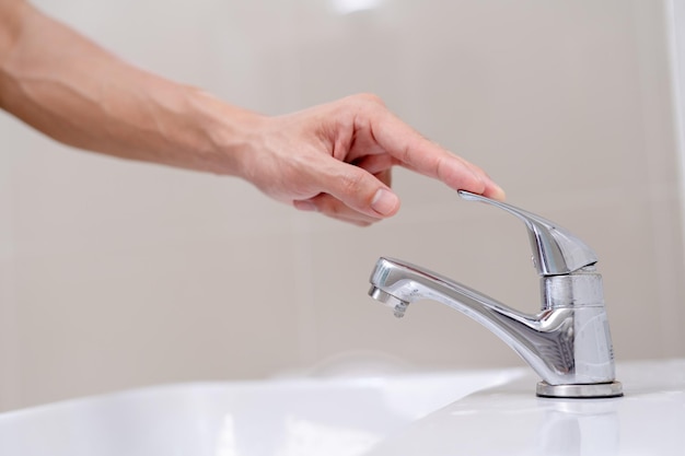 The faucet in the bathroom with running water man turning off\
the water to save water energy and protect the environment world\
environment day