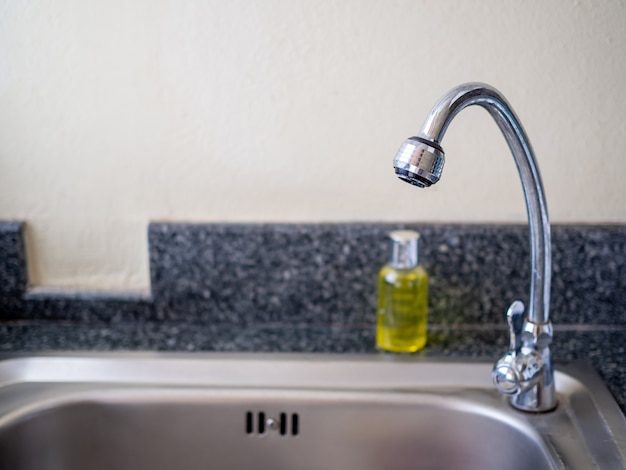 Faucet and bottle of dishwashing liquid On the sink