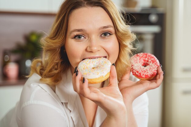 Favorite dessert. Joyful female person biting donut, enjoying the moment