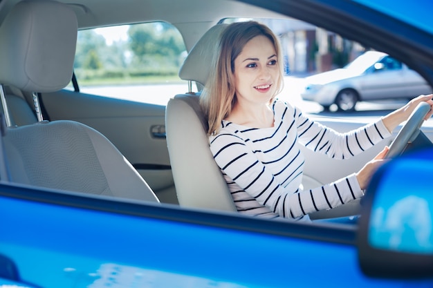 好きな活動。車を運転している間、ハンドルの後ろに座って、笑顔で幸せな素敵な楽しい女性