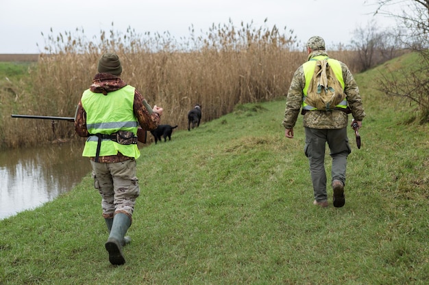 Fazantjagers die met jachtgeweer door een weide lopen.