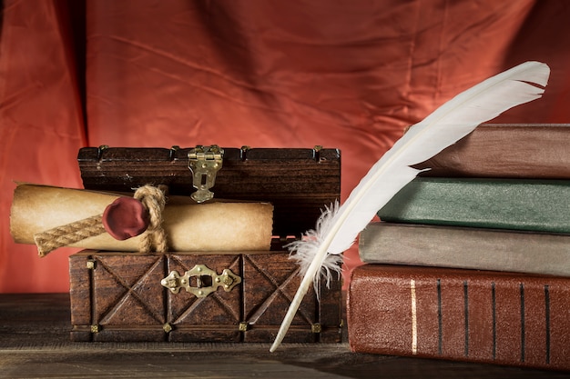 Photo feather near sealed scroll in old chest and vintage books