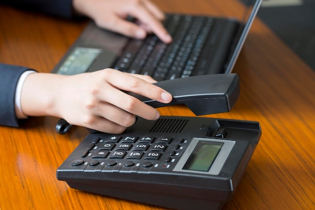 Feature Een vrouw met een telefoon op haar bureau die aan het bellen is