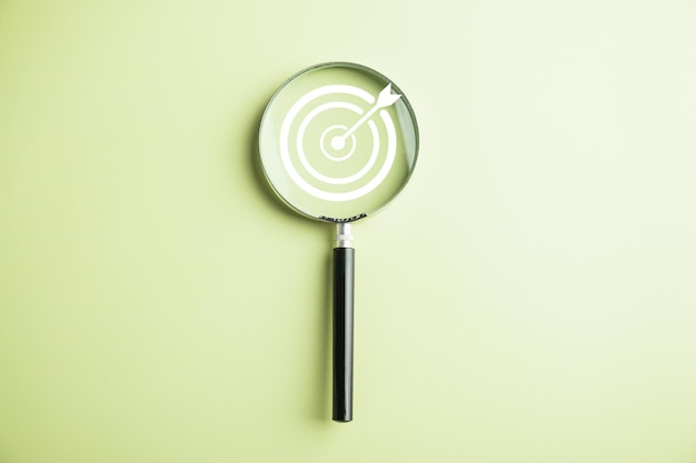 Features a target board captured inside a magnifier glass illustrating the focus on business objectives target search concept and attaining success isolated on a background with copy space