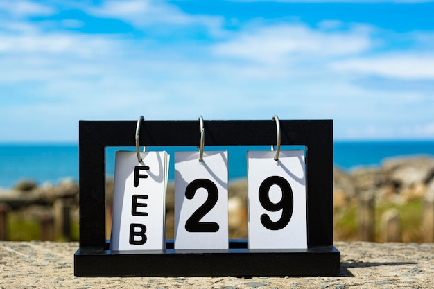 Photo feb 29 calendar date text on wooden frame with blurred background of ocean calendar concept