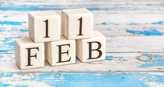 February 11th. Wooden cubes with date of 11 February on old blue wooden background.