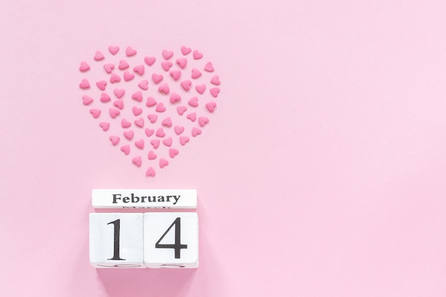 February 14th and heart from pink confectionery sprinkles in a heart shape on pastel pink